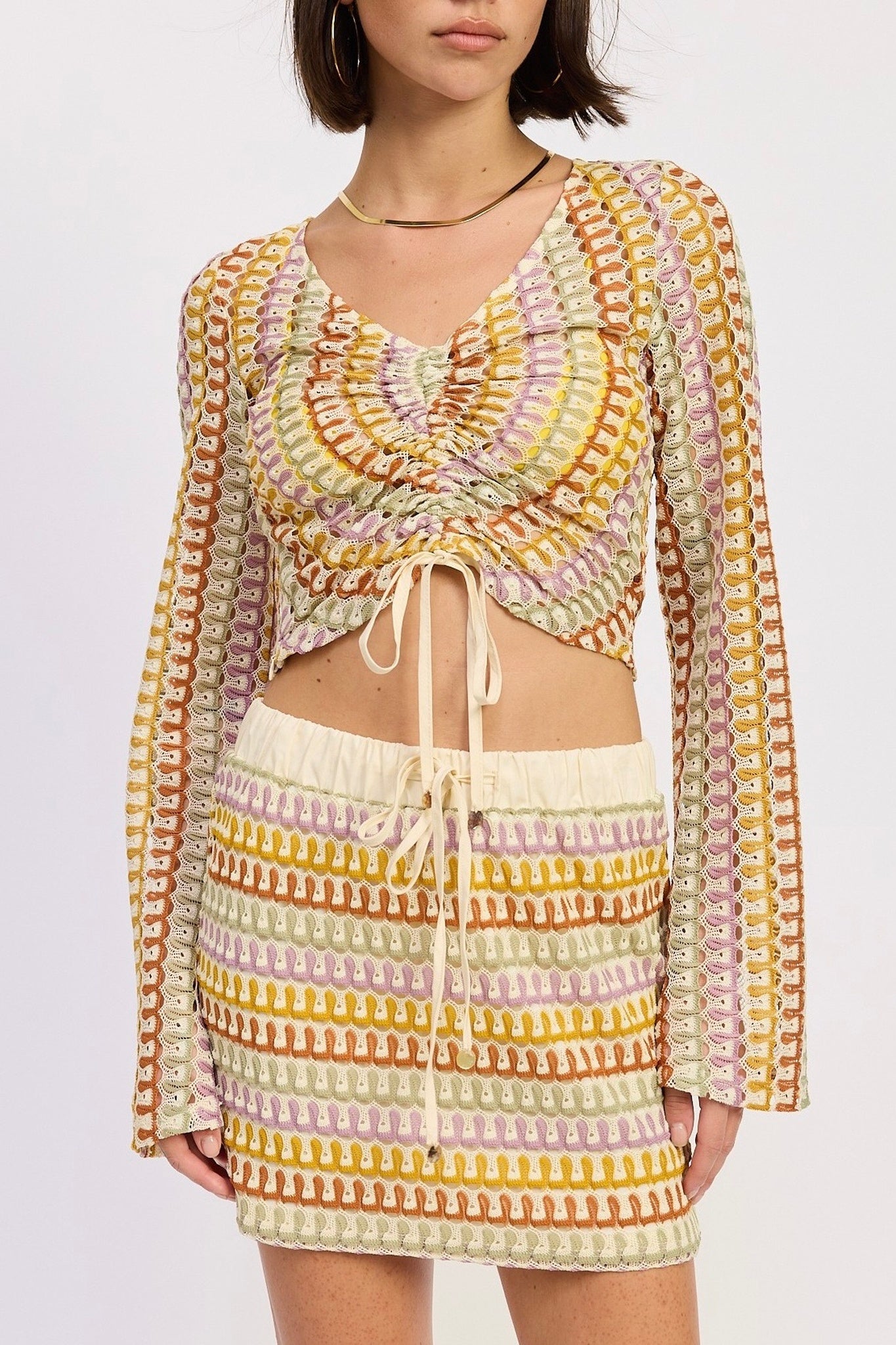 Woman wearing a colorful crochet outfit on a white background