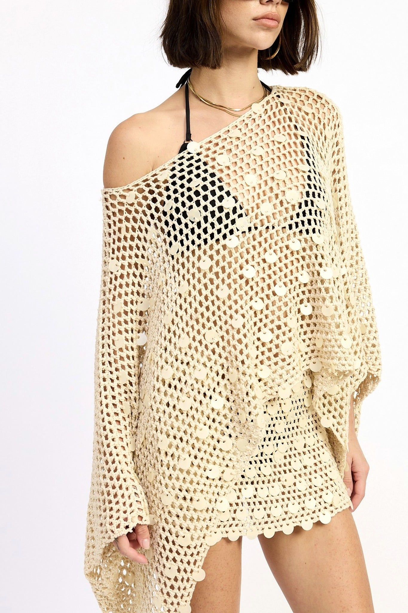 Woman wearing a beige crochet cover-up on a white background