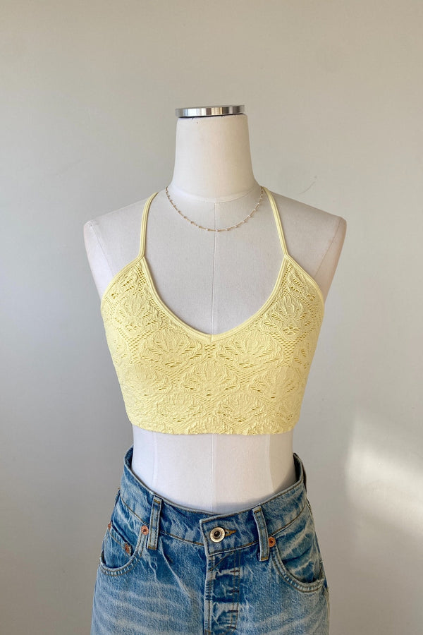 Yellow lace crop top on a mannequin with a plain background