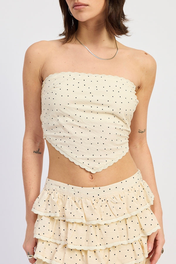 Woman wearing a strapless top and ruffled skirt with polka dot pattern on a white background