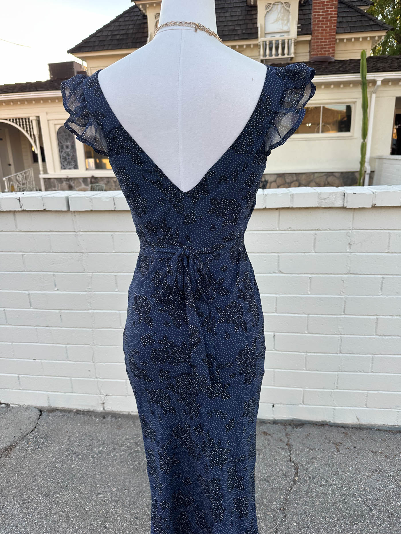 Navy blue lace dress on a mannequin against a white wall.