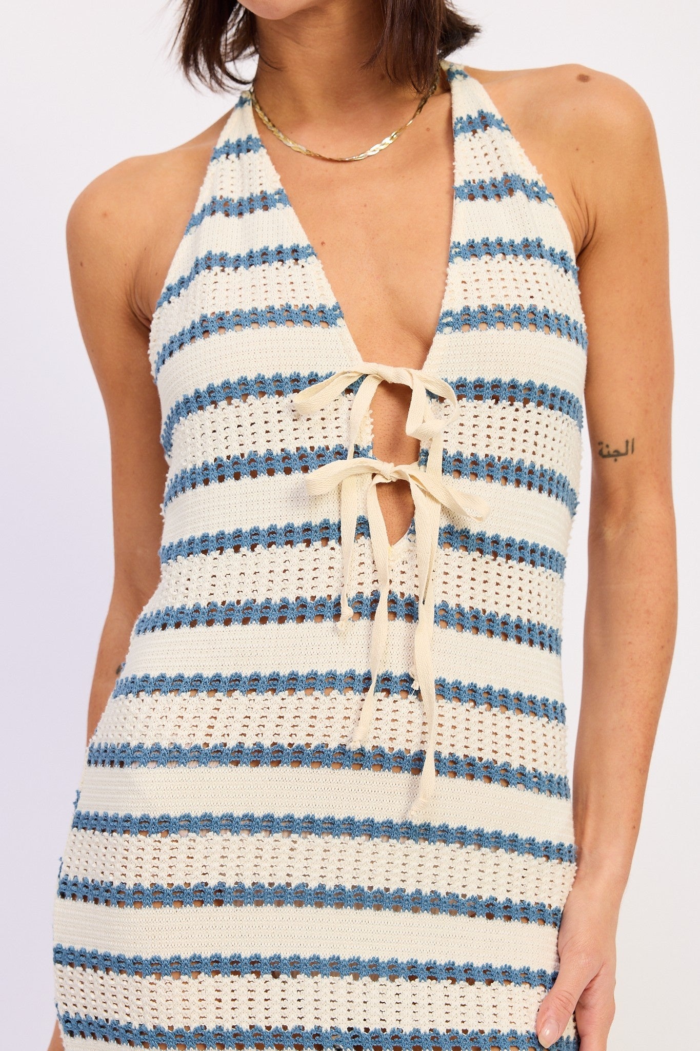 Woman wearing a white and blue striped dress with a deep neckline.