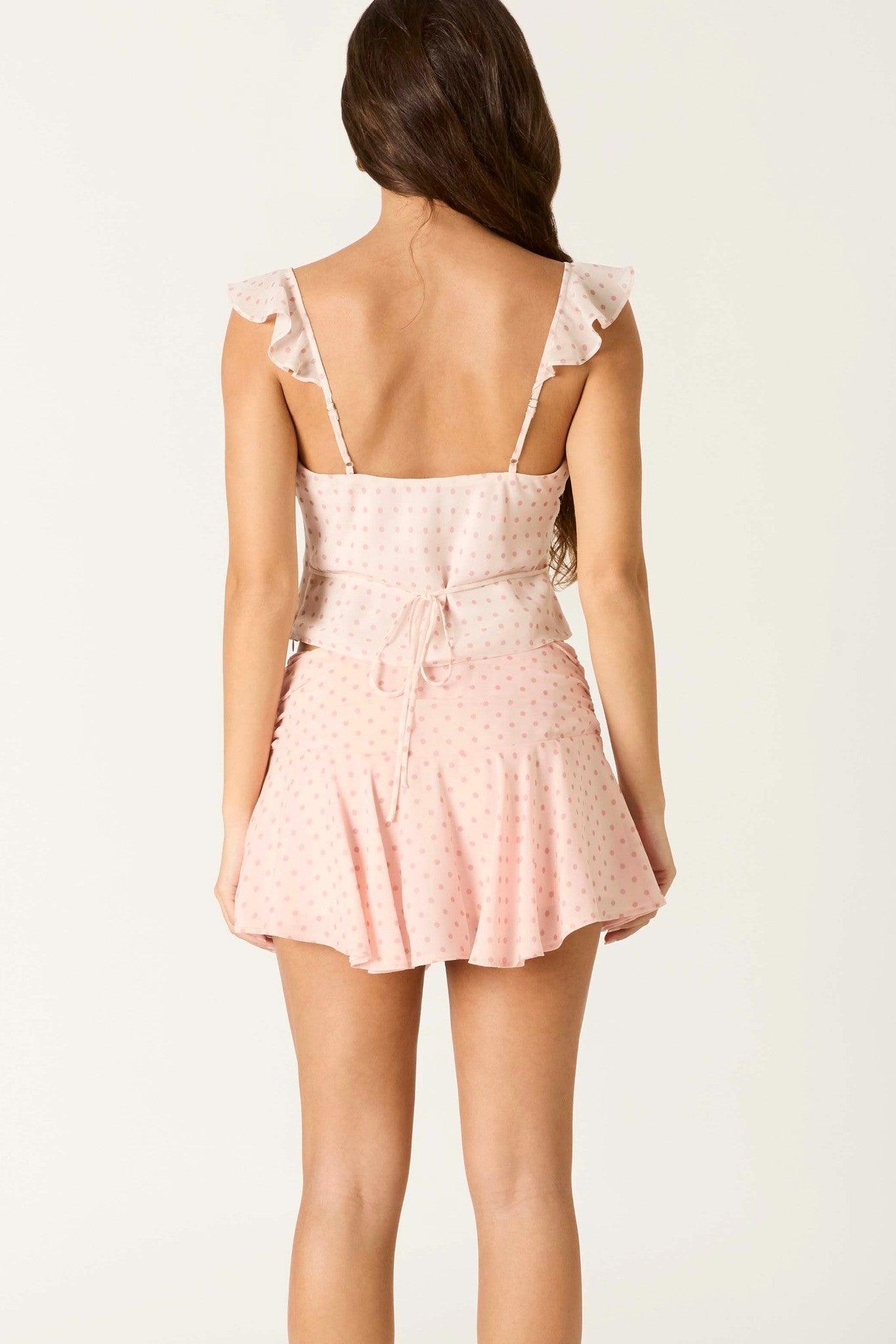 Woman wearing a pink lace romper on a white background